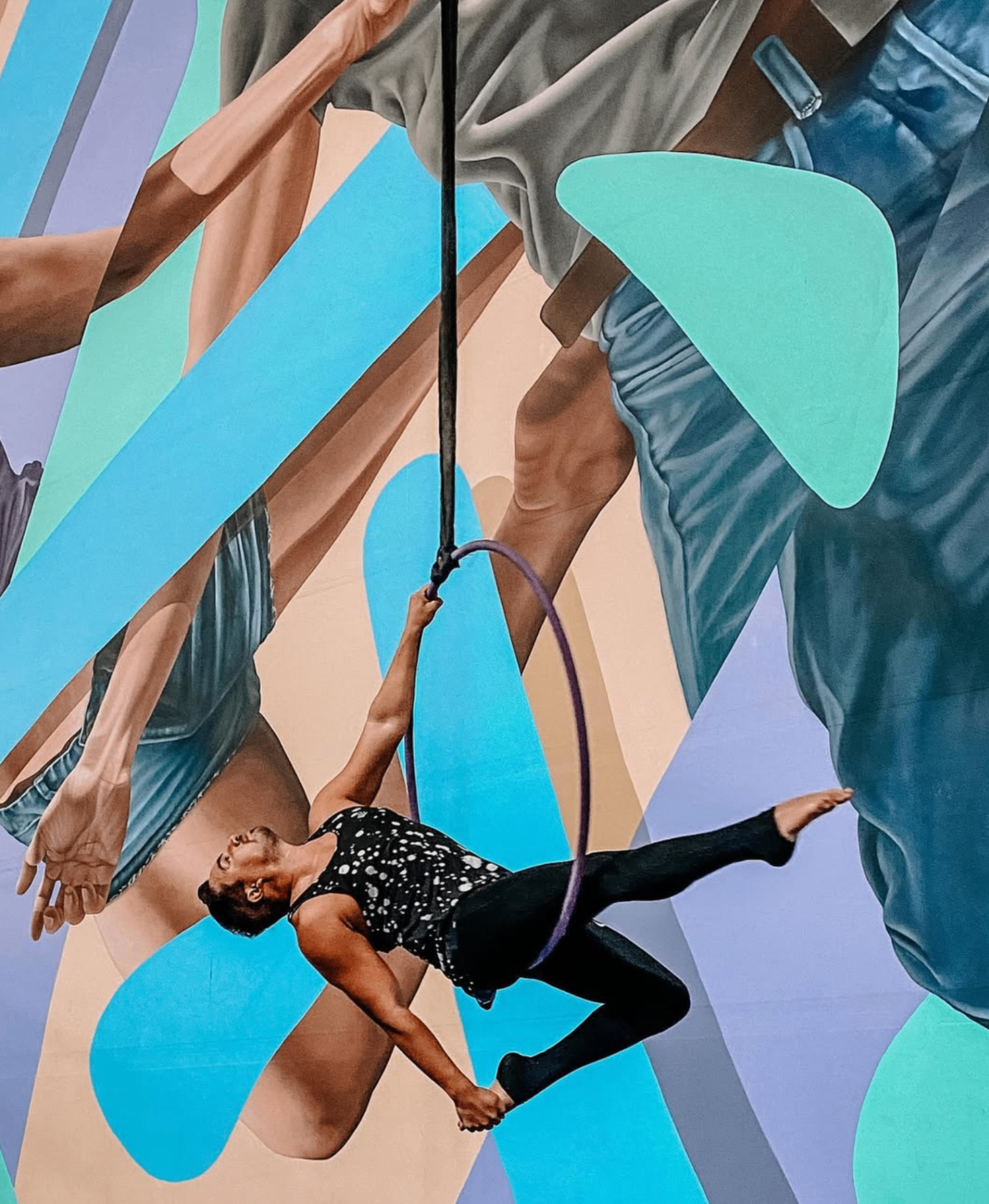 Aerial hoop performer in front of a mural